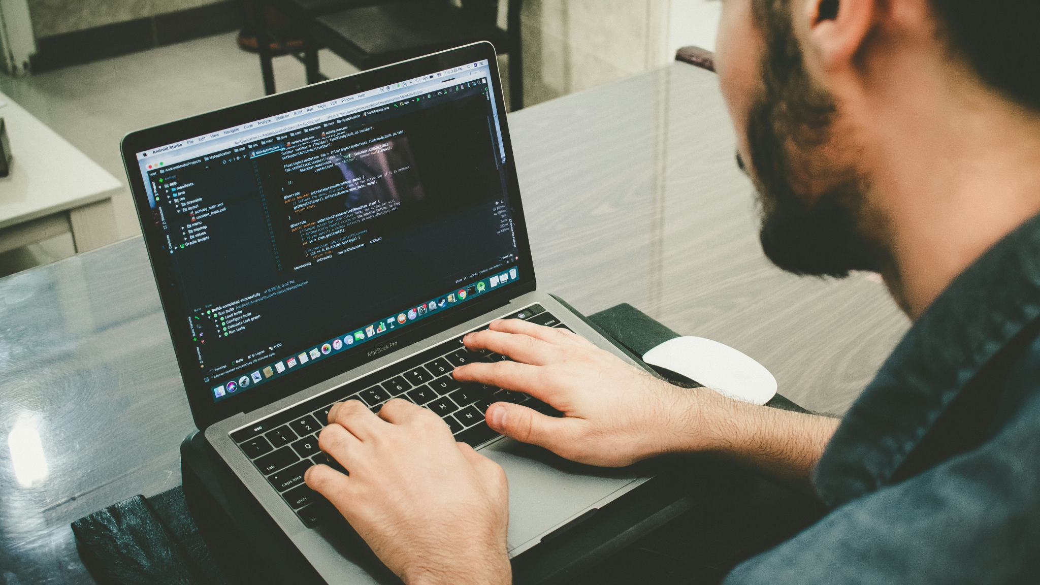 男性がラップトップのコンピュータでプログラミングをしている様子